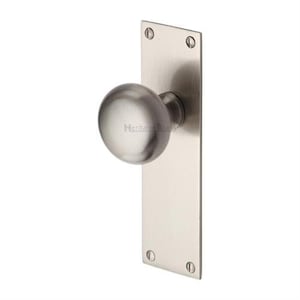 Peut inclure: Un bouton de porte en nickel bross&eacute; avec une poign&eacute;e ronde et une plaque arri&egrave;re rectangulaire. La plaque arri&egrave;re est fix&eacute;e avec quatre vis. Le texte "Heritage Brass" est visible sur le bouton.