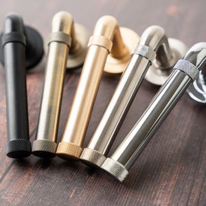 May include: Five different door handles with a variety of finishes, including black, silver, brass, and gold. The handles are all made of metal and have a simple, elegant design.