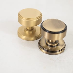 May include: Two round door knobs, one is polished brass and the other is antique brass.