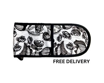 Puede incluir: Un guante de horno doble con un estampado floral en blanco y negro. El guante tiene un borde negro y el texto "FREE DELIVERY" en negro. El diseño floral presenta flores y hojas estilizadas.