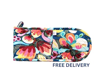 Puede incluir: Una manopla de horno con estampado floral colorido sobre fondo azul. La manopla tiene un lazo para colgar y un bolsillo en el lateral. El texto "ENVÍO GRATIS" está impreso debajo de la manopla.