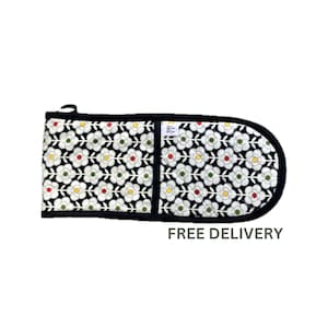 May include: Black oven mitt with a white floral pattern and a black border. The mitt has a pocket on the back. FREE DELIVERY is written in green text below the mitt.