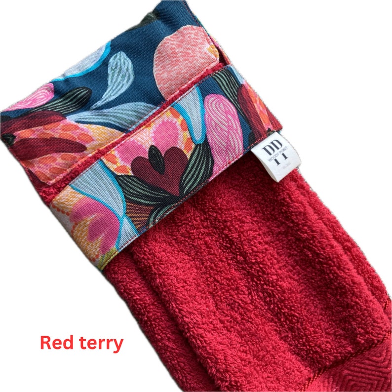 K&ouml;nnte beinhalten: Rotes Frottiertuch f&uuml;r die K&uuml;che mit einem bunten Band aus Stoff mit Blumenmuster. Das Band tr&auml;gt den Text "DD WOODCRAFT".