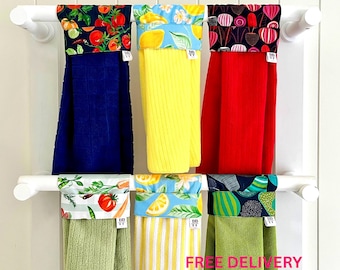 Puede incluir: Seis paños de cocina colgantes con partes superiores de tela estampada y partes inferiores texturizadas lisas o a rayas. Los estampados incluyen tomates, limones, remolachas, verduras y formas abstractas en colores vivos.