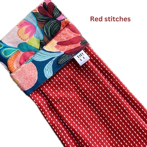 K&ouml;nnte beinhalten: Roter Strumpf mit wei&szlig;en N&auml;hten und einer bunten, floralen Stoffmanschette. Die Manschette hat ein kleines wei&szlig;es Etikett mit dem Text "DD 11 DESIGN DISTRICT".