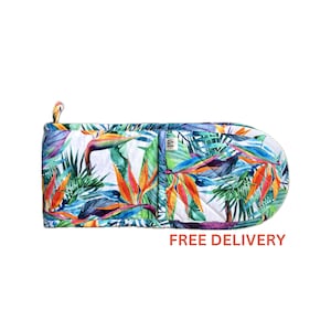 May include: A colourful oven mitt with a tropical print featuring bright orange, yellow, blue, and green bird of paradise flowers and leaves on a white background. FREE DELIVERY.