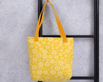 May include: A yellow tote bag with a white daisy pattern. The bag has orange straps.