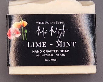 Puede incluir: Una pastilla de jabón artesanal con una etiqueta negra que dice "Wild Poppy Suds Mo' Mojito Lime - Mint Hand Crafted Soap All Natural - Vegan 6oz / 180g". La etiqueta tiene un diseño floral con una flor de amapola.