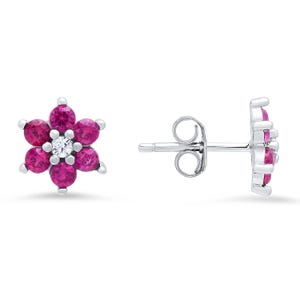 May include: A pair of silver stud earrings shaped like flowers. Each earring features six round, vibrant pink stones arranged as petals surrounding a single, clear, round center stone. The earrings include silver posts and butterfly backings.
