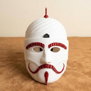 May include: A white mask with red accents, featuring a stylized face with eye and mouth openings. The mask has a curved mustache and eyebrow design, with a red spike on top. The mask is set against a neutral background.
