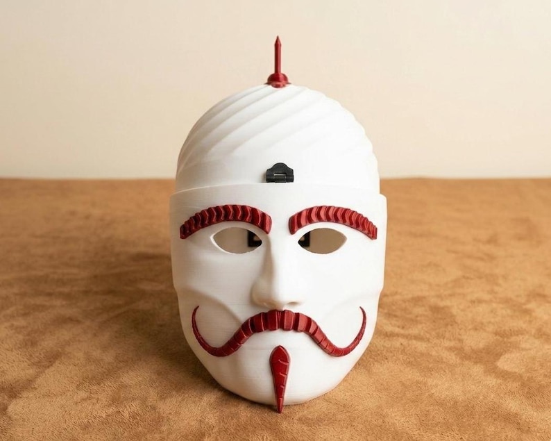 May include: A white mask with red accents, featuring a stylized face with eye and mouth openings. The mask has a curved mustache and eyebrow design, with a red spike on top. The mask is set against a neutral background.