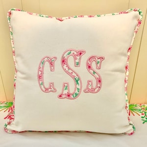 Peut inclure: Un oreiller blanc avec une bordure florale rose et un monogramme floral rose "CSS" au centre.