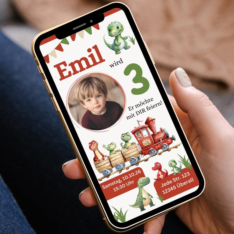 K&ouml;nnte beinhalten: Ein Smartphone zeigt eine Geburtstagseinladung mit einem Kinderfoto. Das Design zeigt einen roten Zug mit Dinosaurier-Passagieren, gr&uuml;ne und rote Akzente und den Text "Emil wird 3". Die Einladung enth&auml;lt Datum, Uhrzeit und Ort.