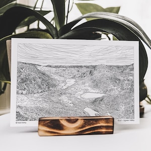 May include: A black and white line drawing of a mountain valley with the text "Eryn - Ogwen Valley" at the bottom right corner.