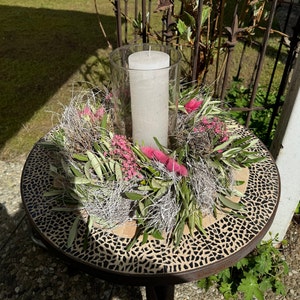Tischkranz als Tischdeko mit Kerze in der Mitte auf einem Garten Tisch