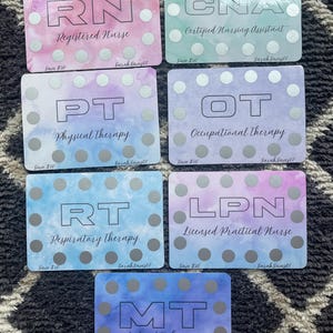 May include: A collection of colorful cards featuring various medical professions: RN, CNA, PT, OT, RT, LPN, and MT. Each card has a watercolor background and silver dot accents. The profession's title is printed in large letters.