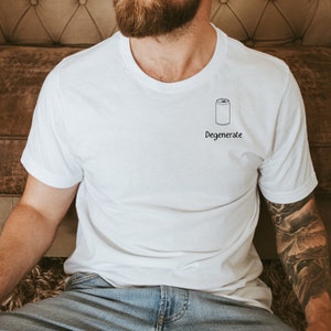 Op de afbeelding: Wit T-shirt met een zwarte illustratie van een blikje en het woord "Degenerate" eronder. Het shirt heeft korte mouwen en een ronde hals.