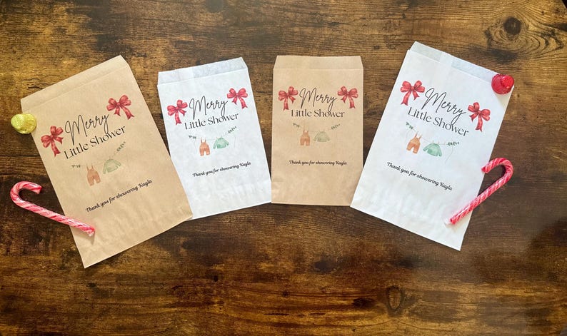 May include: Four paper gift bags with the text "Merry Little Shower" and illustrations of baby clothes. The bags are in shades of brown and white, with red bows and candy canes. A yellow heart and a red ornament are also present.
