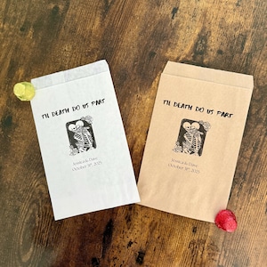May include: Two paper favor bags with the text "Til Death Do Us Part" and a skeleton couple graphic. One bag is white, the other is tan. The bags are personalized with a name and date.