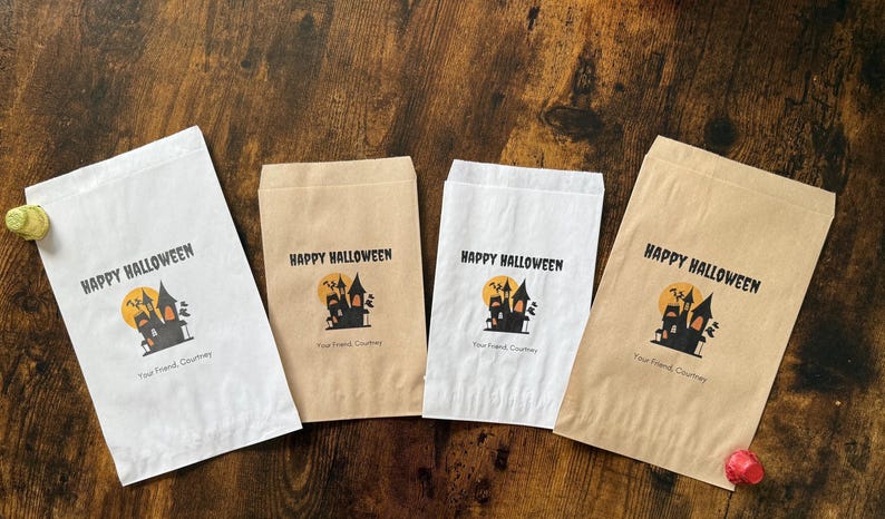 May include: Four paper treat bags with a Halloween theme. Each bag has the words "Happy Halloween" above a graphic of a haunted house and a full moon. The text "Your Friend, Courtney" is below the graphic.