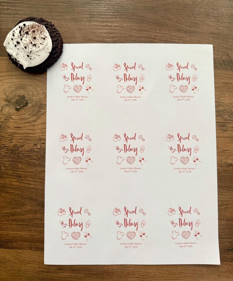 Op de afbeelding: Een wit vel met negen ronde stickers met rode tekst en afbeeldingen. Elke sticker bevat de tekst "Special Delivery" samen met iconen van een babyfles, rammelaar, rompertje, hart en wijnglazen, plus "Jessica's Baby Shower July 19th, 2026".