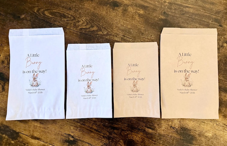 May include: Four paper treat bags in white and tan, with the text "A Little Bunny is on the way!" and a bunny illustration. The bags are for Violet's Baby Shower, March 18th, 2026.