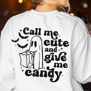 May include: White sweatshirt with a black graphic on the back. The graphic features a ghost holding a candy bag, bats, and the text "Call me cute and give me candy."
