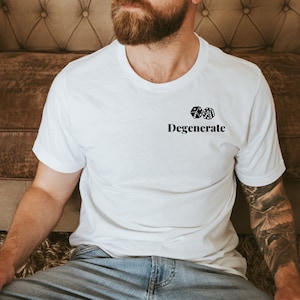 Pu&ograve; includere: T-shirt bianca con la scritta "Degenerate" sotto due dadi. Il design &egrave; in nero. La maglietta &egrave; realizzata in un materiale morbido, adatta per un abbigliamento casual.