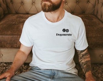 Op de afbeelding: Wit T-shirt met het woord "Degenerate" onder twee dobbelstenen. Het ontwerp is zwart. Het shirt is gemaakt van een zacht materiaal, geschikt voor casual wear.