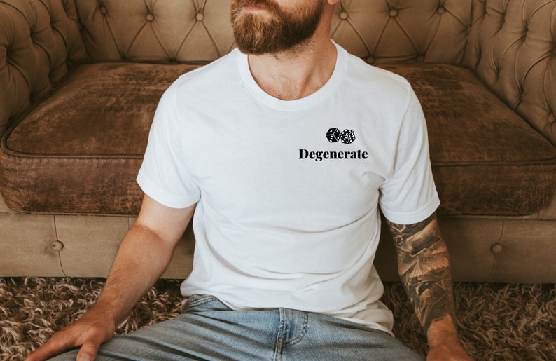 Pu&ograve; includere: T-shirt bianca con la scritta "Degenerate" sotto due dadi. Il design &egrave; in nero. La maglietta &egrave; realizzata in un materiale morbido, adatta per un abbigliamento casual.