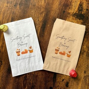 May include: Two paper treat bags, one white and one brown, with the text "Something Sweet is Brewing". Each bag features illustrations of coffee, pie, and cupcakes. The text "Thank you for showering Jessica" is printed below.