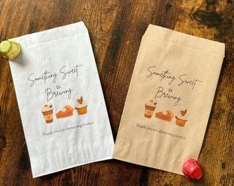 May include: Two paper treat bags, one white and one brown, with the text "Something Sweet is Brewing". Each bag features illustrations of coffee, pie, and cupcakes. The text "Thank you for showering Jessica" is printed below.
