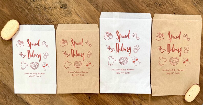 May include: Four rectangular paper bags in white and brown kraft paper, featuring red printed graphics of baby items, pizza, and wine glasses. The text reads Special Delivery, Jessica's Baby Shower, and July 15th, 2026, with two oval cookies.