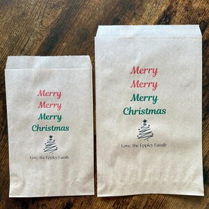 May include: Two brown paper gift bags with the words "Merry Christmas" printed in red and green. A small Christmas tree graphic is below the text, and the words "Love, the Eppley Family" are printed below the tree.