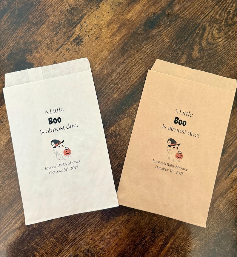 K&ouml;nnte beinhalten: Zwei Papiert&uuml;ten, eine wei&szlig;e und eine beige, mit dem Text "A Little Boo is almost due!" und einer Geistergrafik. Die T&uuml;ten sind f&uuml;r Jessicas Babyparty, 31. Oktober 2025.