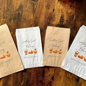 May include: Four paper bags with the text "Something Sweet is Brewing" and illustrations of coffee cups, bread, and cupcakes. The bags are in shades of brown and white, with a wooden background.
