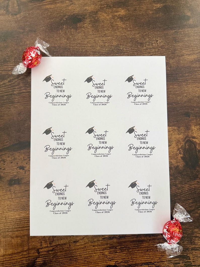 K&ouml;nnte beinhalten: Ein Bogen wei&szlig;er Aufkleber mit dem Text "Sweet Endings to New Beginnings" und einer Abschlusskappe. Die Aufkleber sind f&uuml;r den Jahrgang 2020. Zwei rot-silberne Bonbons liegen auf der Holzoberfl&auml;che.