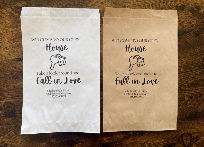 May include: Two paper bags, one white and one tan, with the text "WELCOME TO OUR OPEN HOUSE" and "Take a look around and Fall in Love." A key and house graphic is in the center. The bags also display a real estate company's name and phone number.
