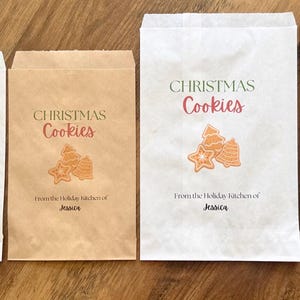 May include: Four rectangular paper bags in white and brown, featuring the printed text CHRISTMAS Cookies and From the Holiday kitchen of Jessica, accompanied by a graphic illustration of three assorted holiday-themed cookies.