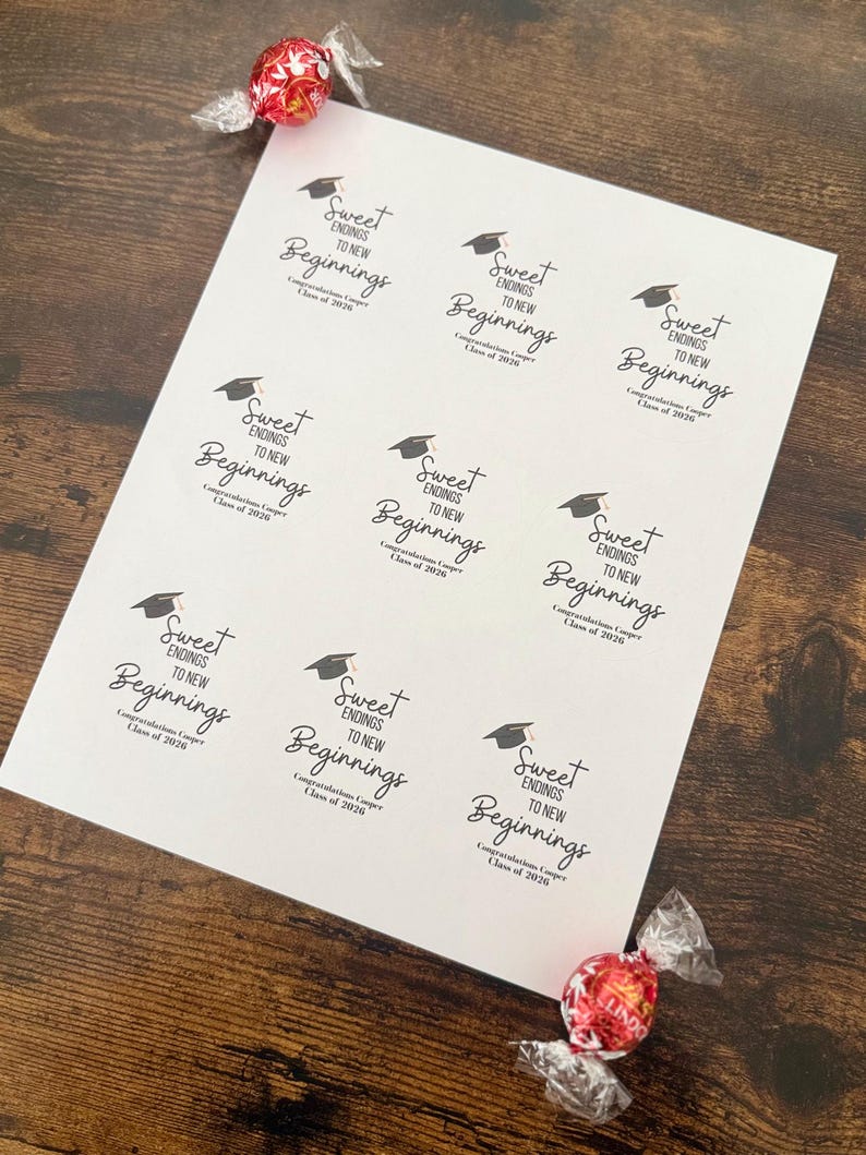 K&ouml;nnte beinhalten: Ein wei&szlig;es Blatt Papier mit dem Text "Sweet Endings to New Beginnings" und einer Abschlusskappe. Der Text enth&auml;lt "Class of 2020". Zwei verpackte S&uuml;&szlig;igkeiten befinden sich im Bild. Das Papier liegt auf einer Holzoberfl&auml;che.