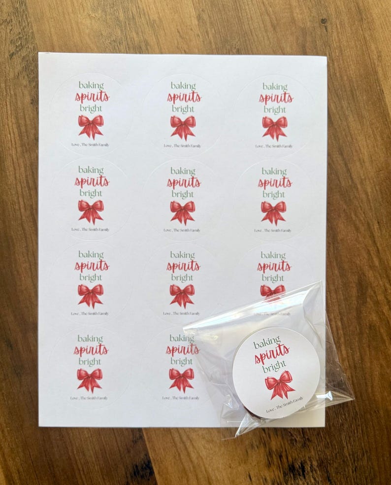 May include: A sheet of twelve circular white stickers featuring the red text baking spirits bright above a red bow illustration and the black text Love, The Smith Family. One additional sticker is enclosed in a clear plastic bag.