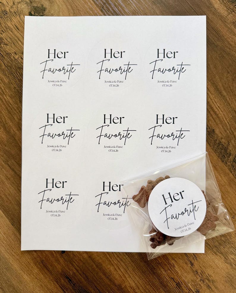 Peut inclure: Une feuille de papier blanc avec huit autocollants circulaires portant le texte noir Her Favorite, Jessica & Dave, et 07.14.26. Un autocollant suppl&eacute;mentaire est coll&eacute; sur un sachet plastique transparent contenant des petits &eacute;l&eacute;ments bruns.