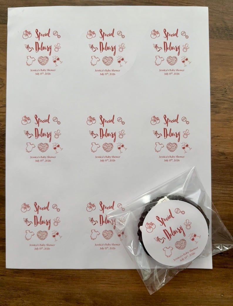 Op de afbeelding: Een vel met acht ronde witte stickers met rode tekst Special Delivery en Jessica's Baby Shower July 15th, 2026, met iconen van een rammelaar, fopspeen, rompertje, hart en wijnglazen. E&eacute;n sticker zit in een doorzichtig plastic zakje.