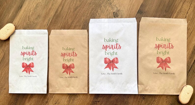 May include: Four rectangular paper bags in white and brown kraft paper. Each bag features the text 'baking spirits bright' in green and red, a red bow illustration, and the personalised text 'Love, The Smith Family' at the bottom.