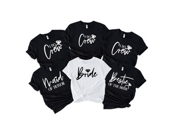 Può includere: Una collezione di magliette bianche e nere con testo a tema addio al nubilato. Le magliette includono frasi come "I Do Crew", "Maid of Honor", "Bestie of the Bride" e "Bride". Le magliette sono a maniche corte e hanno un girocollo.