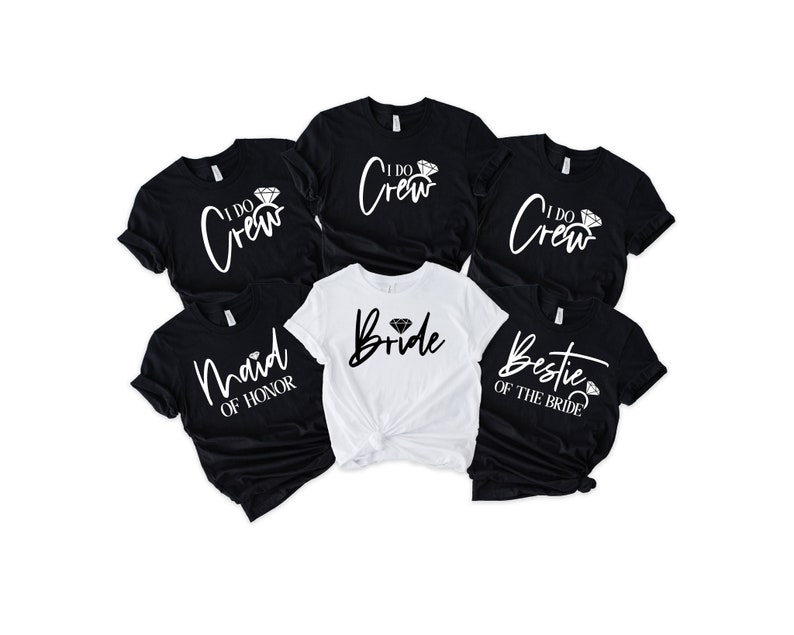 Peut inclure: Plusieurs t-shirts noirs et blancs avec des inscriptions sur le th&egrave;me du mariage. Les chemises comportent des phrases telles que "I Do Crew", "Maid of Honor", "Bestie of the Bride" et "Bride". Les t-shirts sont &agrave; manches courtes et ont un col rond.
