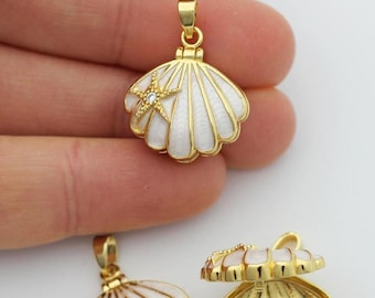 May include: Gold-toned seashell pendants with white enamel and a starfish accent. One pendant is open, revealing the interior. The pendants are likely for jewelry making or crafting.