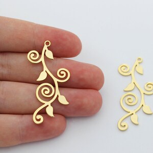 May include: Two gold-colored metal charms shaped like a vine with leaves and swirls.