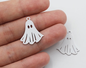Pode incluir: Dois pingentes de fantasma de metal branco com um furo na parte superior para pendurar. Os fantasmas têm um design simples com dois olhos.