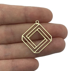 Pode incluir: Pingente de metal dourado com um design quadrado geométrico. O pingente tem um laço na parte superior para prender a uma corrente ou cordão.